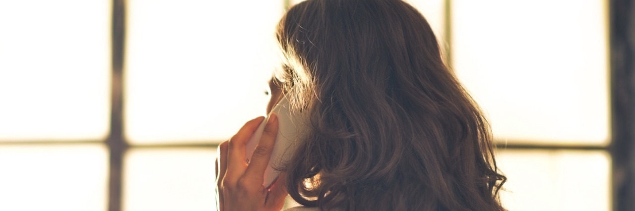 After the Doctor Told Me My Biopsy Came Back Positive for Cancer Woman talking on cell phone in front of window