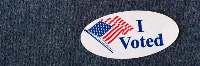 closeup of an american i voted sticker placed on a navy shirt