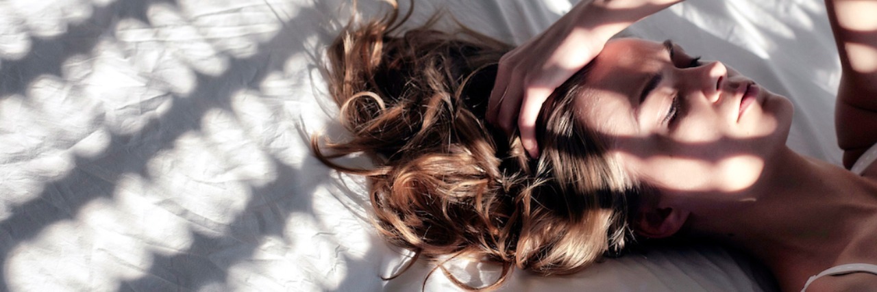 Why We Want Loved Ones to Understand What Anxiety Feels Like woman laying in bed with her hand on her head