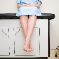 patient sitting in doctor's office with legs dangling over the bed