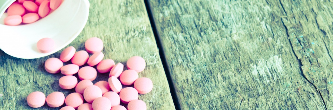 pink bills falling out of a pill bottle