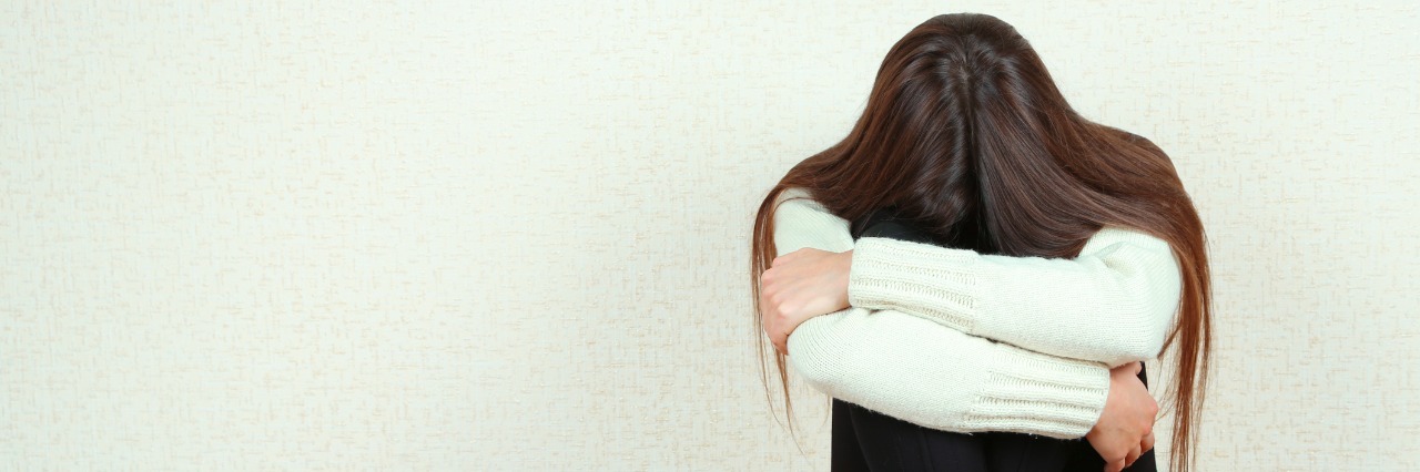 Why Asking for Help Is Hard When You Have Health Problems Sad woman sitting on floor near wall