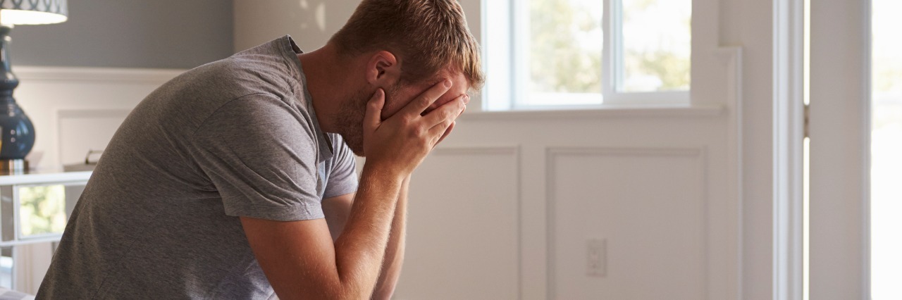 Symptoms of Being Tired as Someone With Ehlers-Danlos Syndrome man sitting on his bed in pajamas with his head in his hands