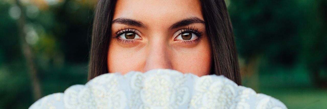 Answering 'How Are You?' When You Live With Depression and Anxiety A woman with her face partially covered by a fan