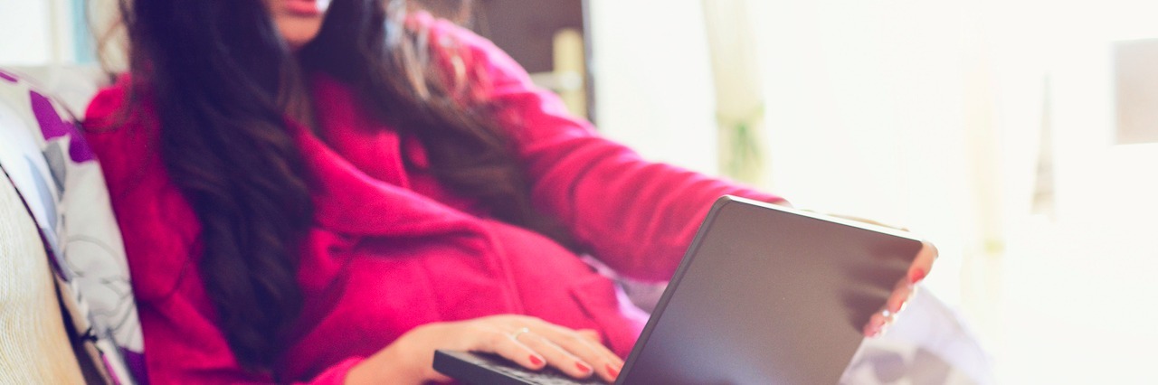 How Netflix and Yoga Pants Help Me Cope With Anxiety and Depression woman laying in bed with her PJs on watching a show on her laptop