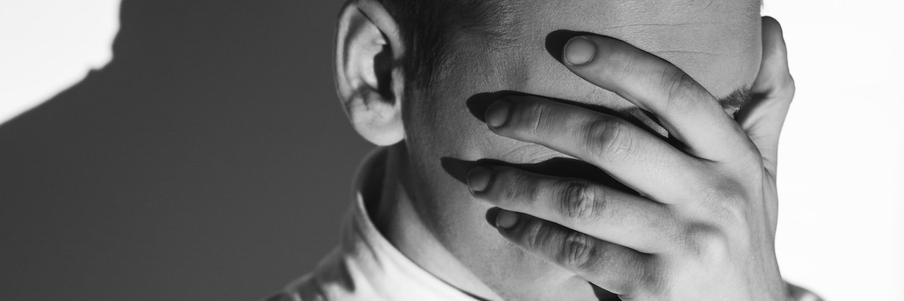 What It's Like to Be in a Psych Hospital a young man covering his face with his hand