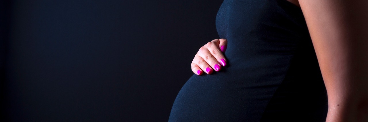 young pregnant woman standing with her hands on her belly