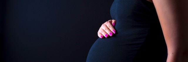 young pregnant woman standing with her hands on her belly