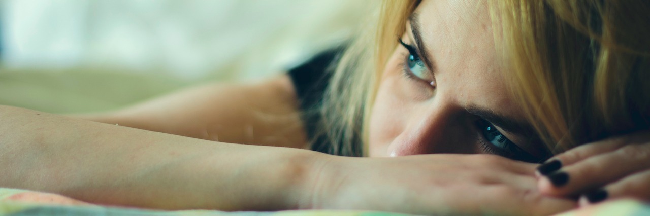 The Difference Between Active and Passive Suicidal Thoughts woman laying down on a bed, looking upset