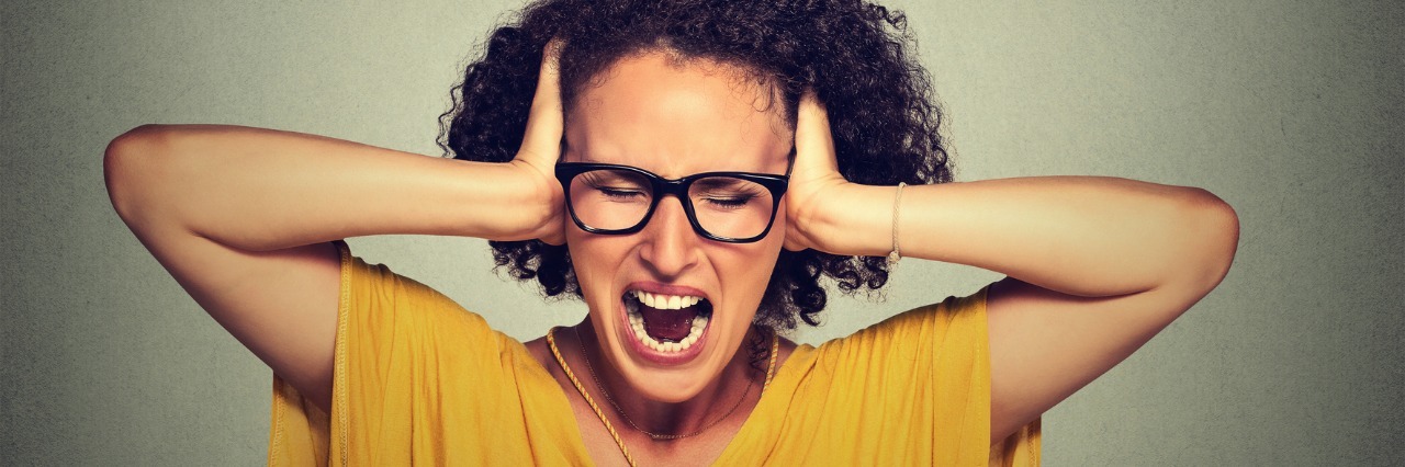What People Get Wrong About Hypothyroidism woman in yellow shirt screaming with her hands covering her ears