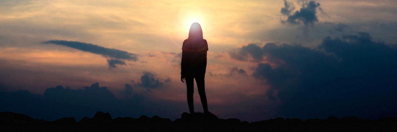 A Letter to Myself During My Lowest Point of Mental Illness a woman standing on a mountain looking at the sunset