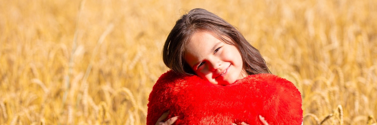 What Life Looks Like When Parenting a Child With a Rare Heart Defect Little girl with heart shaped pillow in the wheat field. Girl cuddling with heart