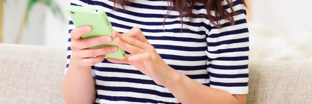 Social Media and Missing Out When You're Sick woman sitting on couch looking at smartphone