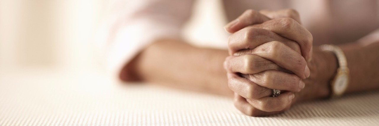 Letter to the Loved Ones of People With Chronic and Mental Illness senior woman sitting at table with hands clasped