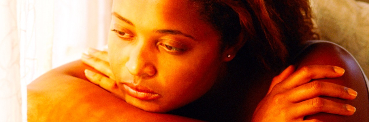 The Worries of a Woman With Bipolar Disorder Who Wants a Baby young woman sitting by a window looking sad