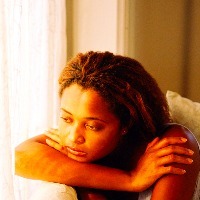 young woman sitting by a window looking sad