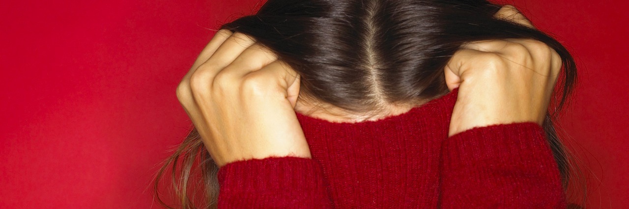 What It's Like When You Can't Hide Your Mental Illness woman hiding under her sweatshirt