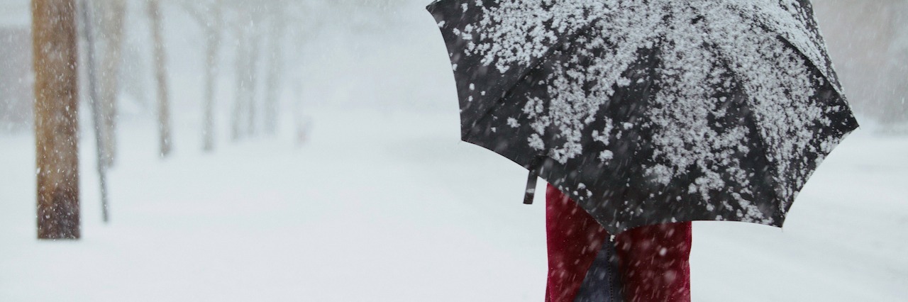a woman walking through a snowstorm holding an umbrella