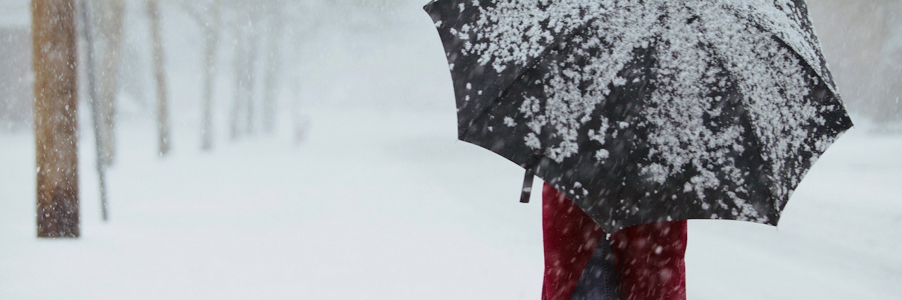When Seasonal Depression Affects You During Winter and Fall a woman walking through a snowstorm holding an umbrella