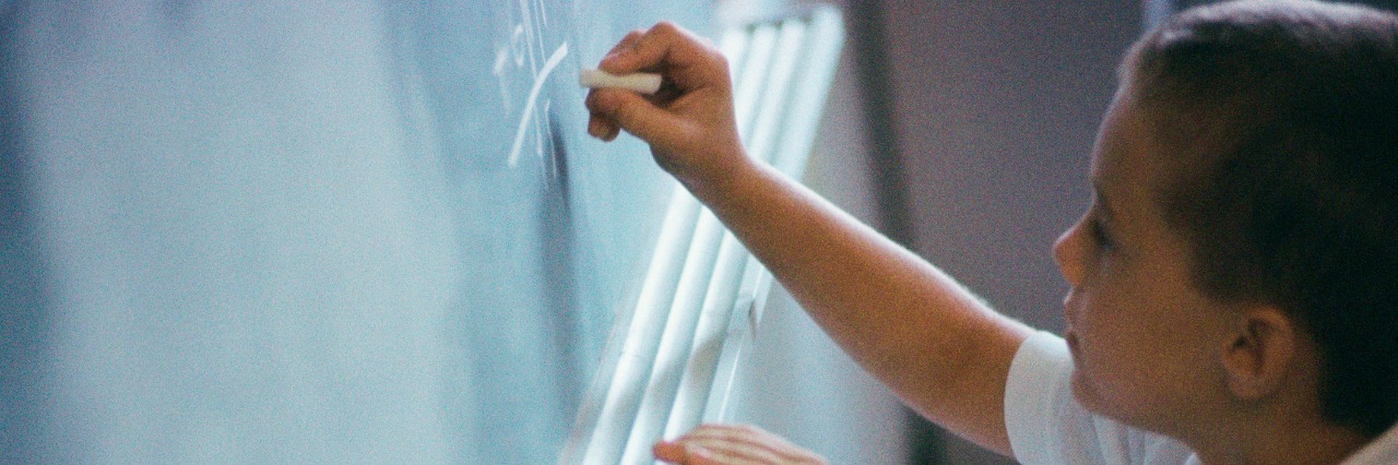 High angle view of a boy writing on a blackboard
