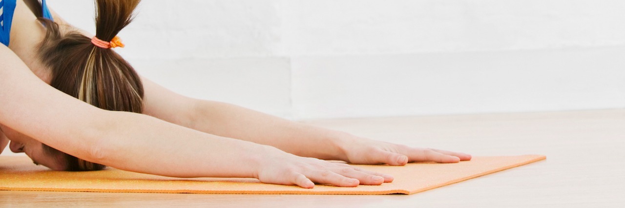 woman doing child's pose on a yoga mat