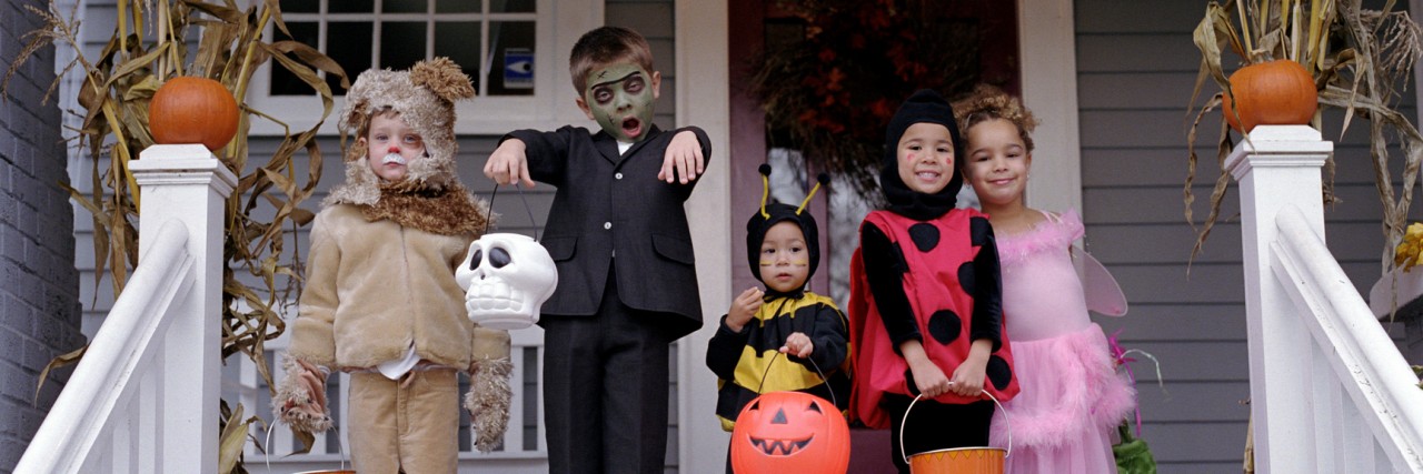 Halloween and PTSD: How to Handle Trick-or-Treaters Five children standing on porch, wearing Halloween costumes, portrait