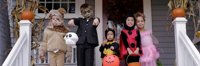 Five children standing on porch, wearing Halloween costumes, portrait