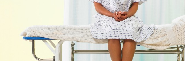 Female patient sitting on gurney in hospital gown