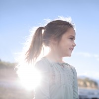 Close-up of young girl (6-7) at beach, backlit