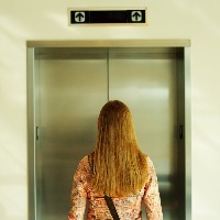 back of a blonde woman waiting for the elevator