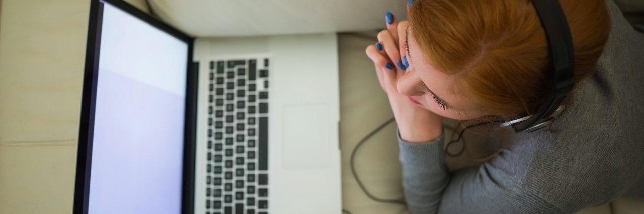 woman using her laptop and wearing headphones