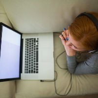 woman using her laptop and wearing headphones