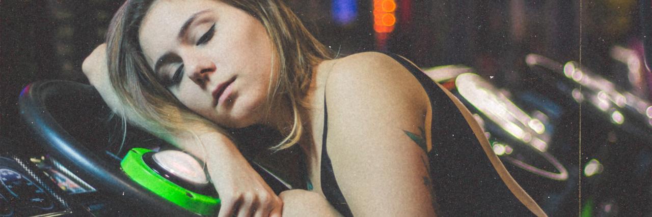Stop Doubting My Chronic Fatigue Is Real photo of woman asleep in arcade on racing game wheel