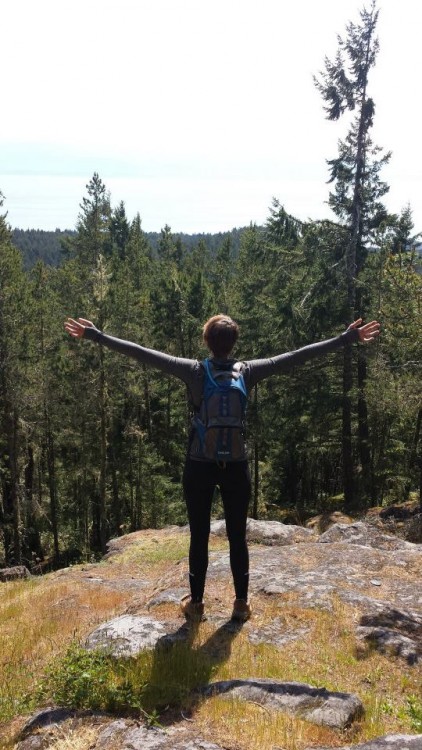 A woman hiking at a cliff with her arms outstretched