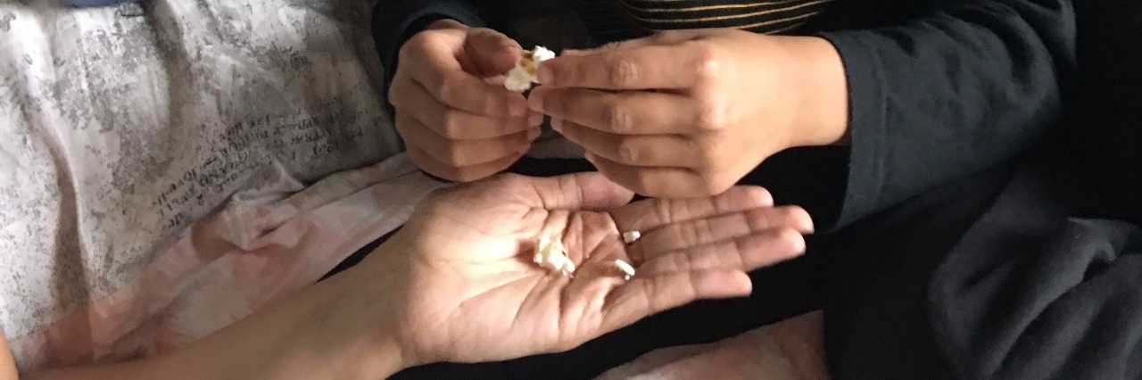 Autism: Encouraging My Son to Try New Foods Boy on bed, taking popcorn from someone's hand