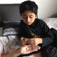 Boy on bed, taking popcorn from someone's hand