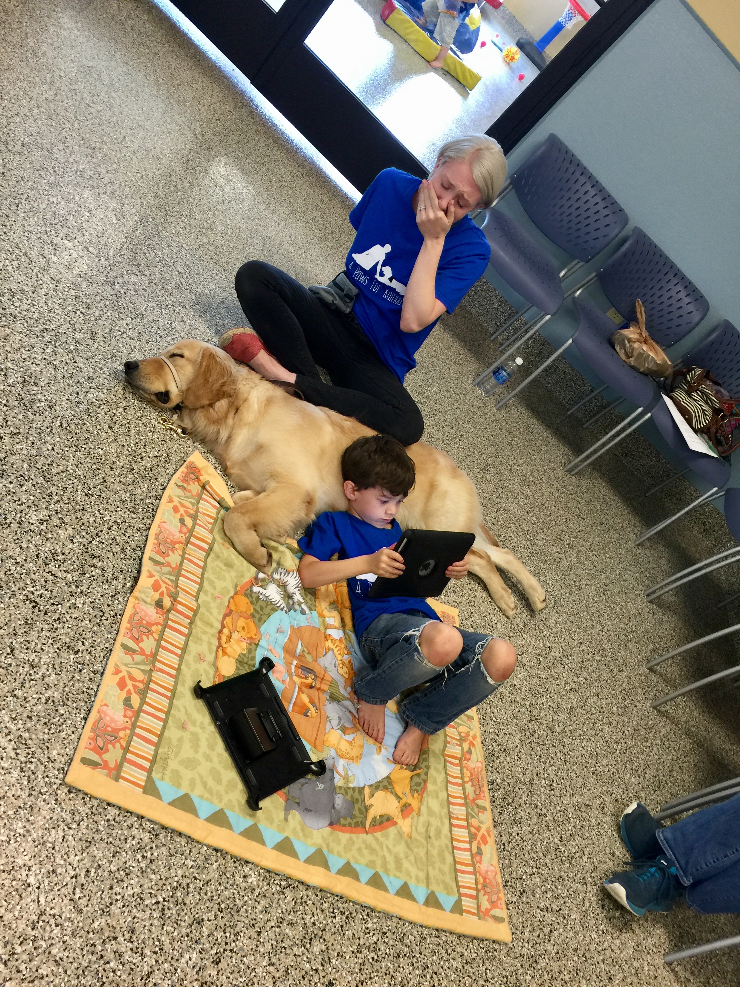 Mother crying and holding a hand to her mouth as her son lies against his new service dog