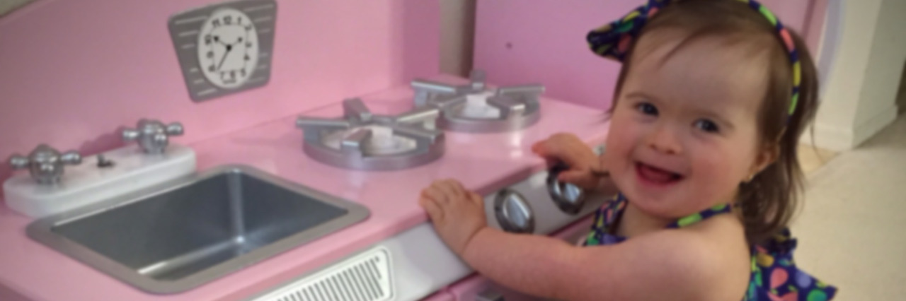Maria's daughter playing in a pink child's kitchen.