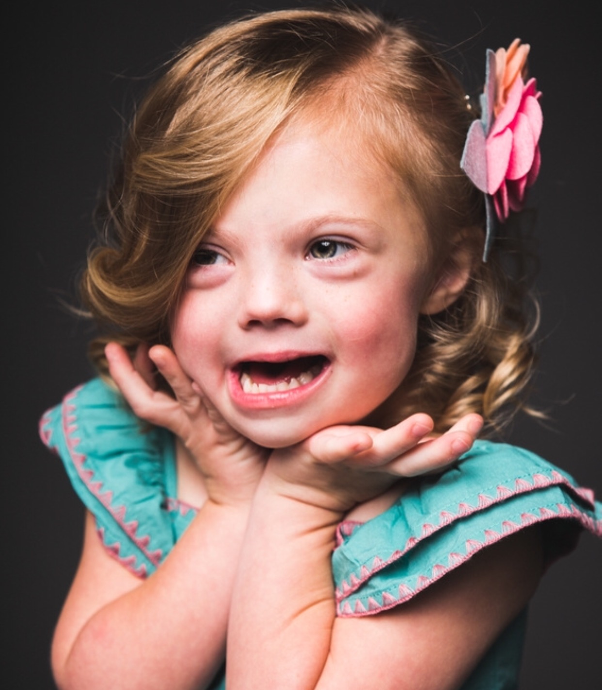 Girl smiling for photo with palms under her chin