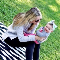 woman sitting outside on a zebra print blanket holding her young daughter