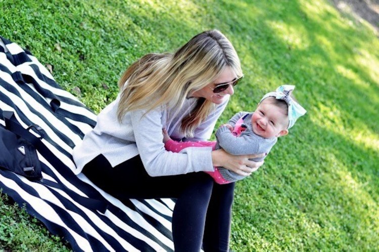 woman sitting outside on a zebra print blanket holding her young daughter