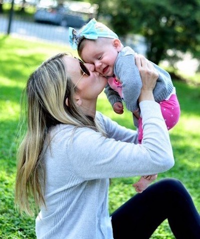 woman kissing her baby daughter outside