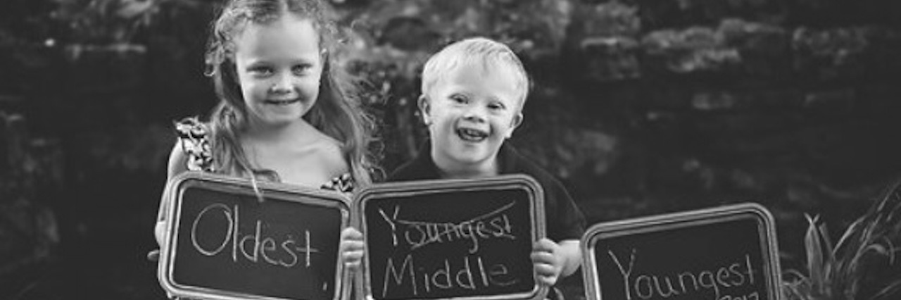 sister and brother holding signs for pregnancy announcement photoshoot