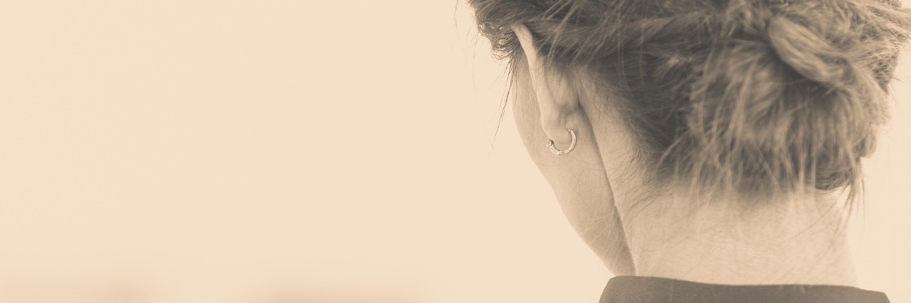 The Isolation of Lyme Disease and Chronic Invisible Illness People and solitude concept. Alone woman looking through window waiting back view indoor