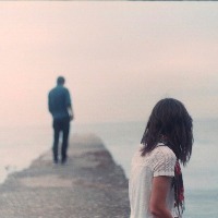 a woman looks at a man standing away from her on a lonely path