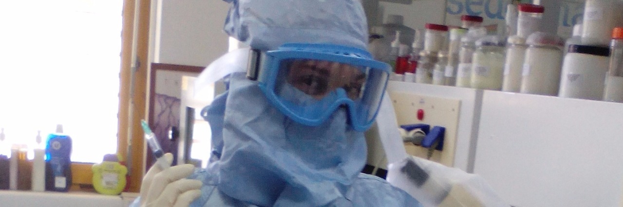 woman wearing scrubs and goggles in science lab