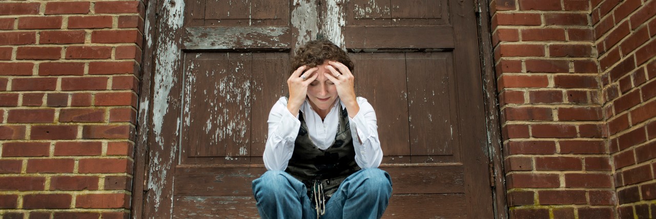 woman upset in front of a brick wall