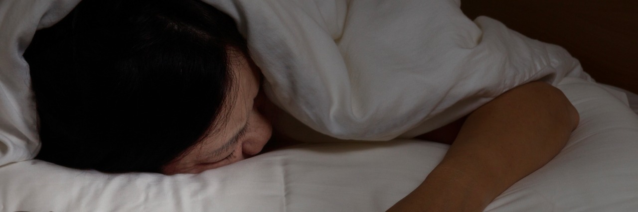 Different Kinds of Tired and What to Do If You're Tired woman sleeping face down with hand outside blanket