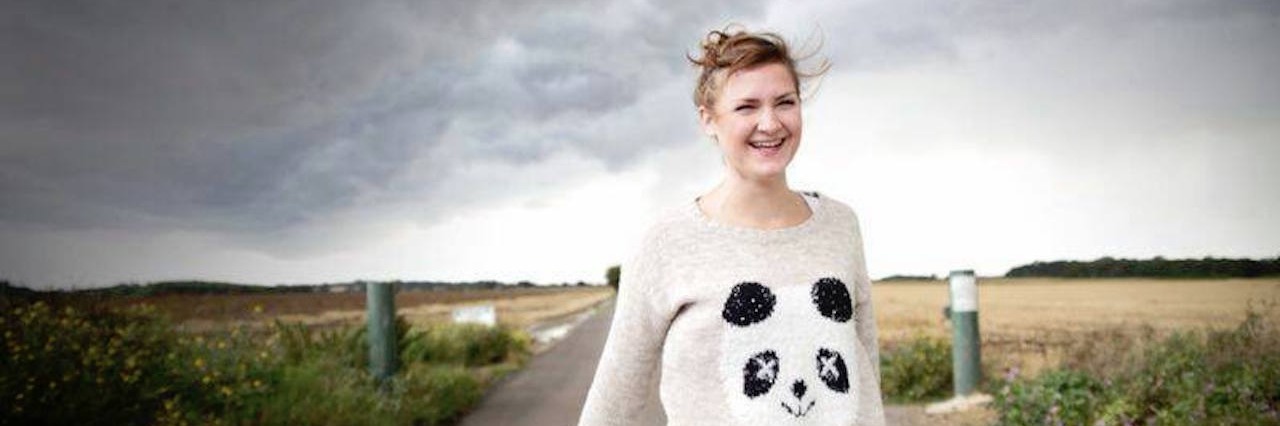 Learning Lessons From Ehlers-Danlos Syndrome woman wearing a panda sweater walks down a road with dark storm clouds behind her