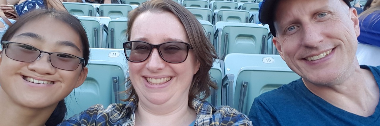 man, woman and child smiling from their seats at a baseball game